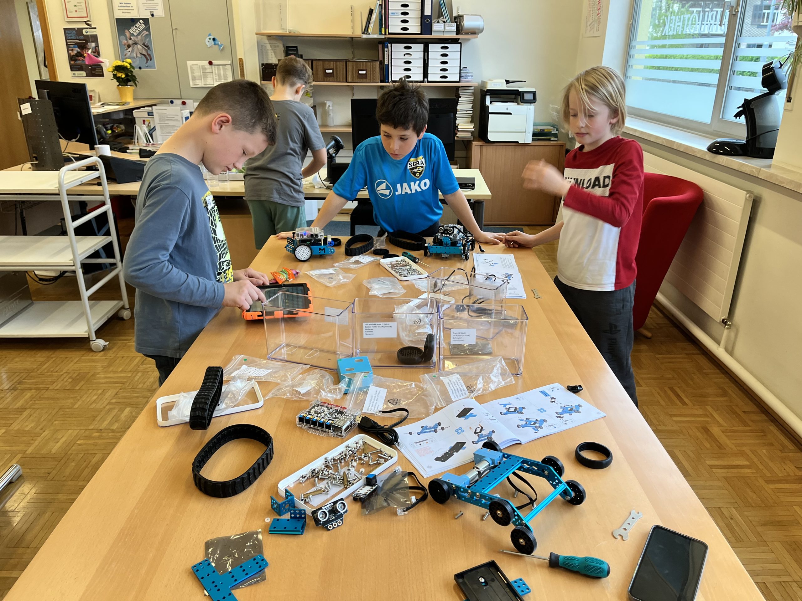 Kinder vor den Bauteilen eines Roboters
